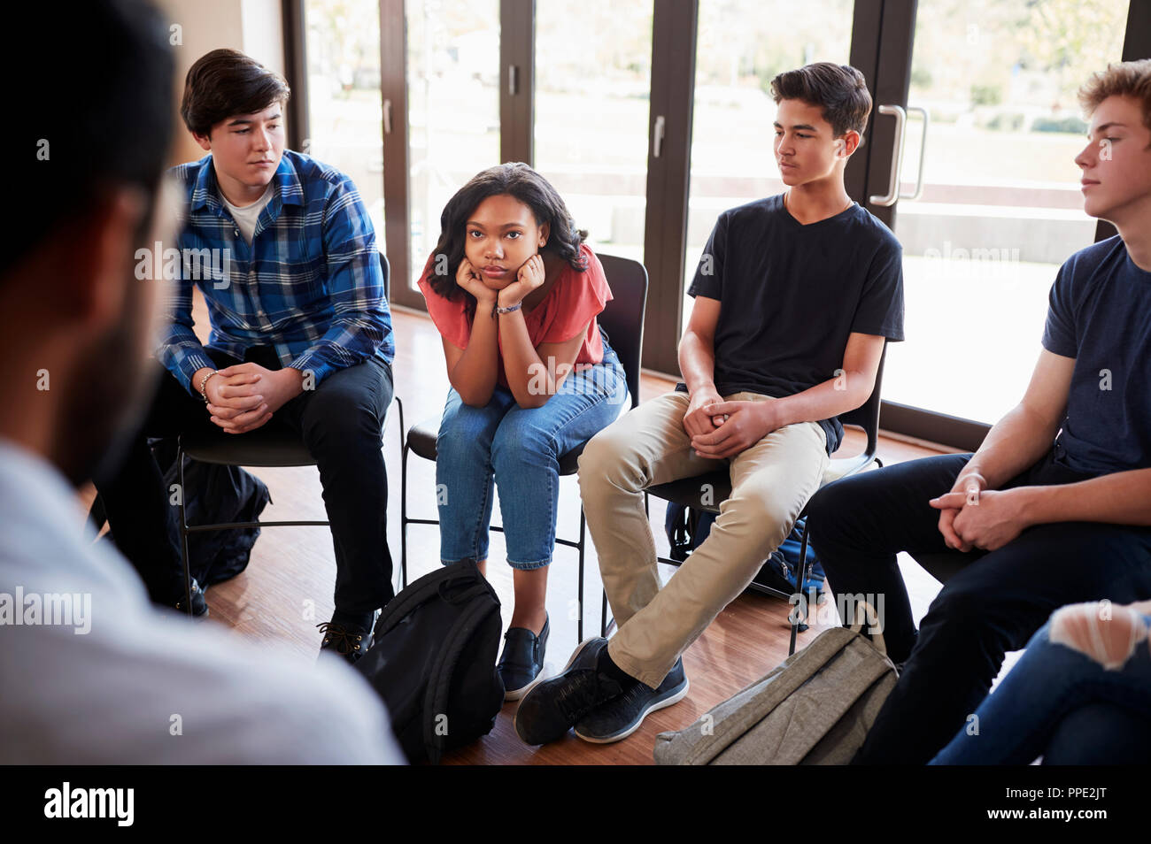 Unhappy Female Pupil In High School Discussion Group Stock Photo