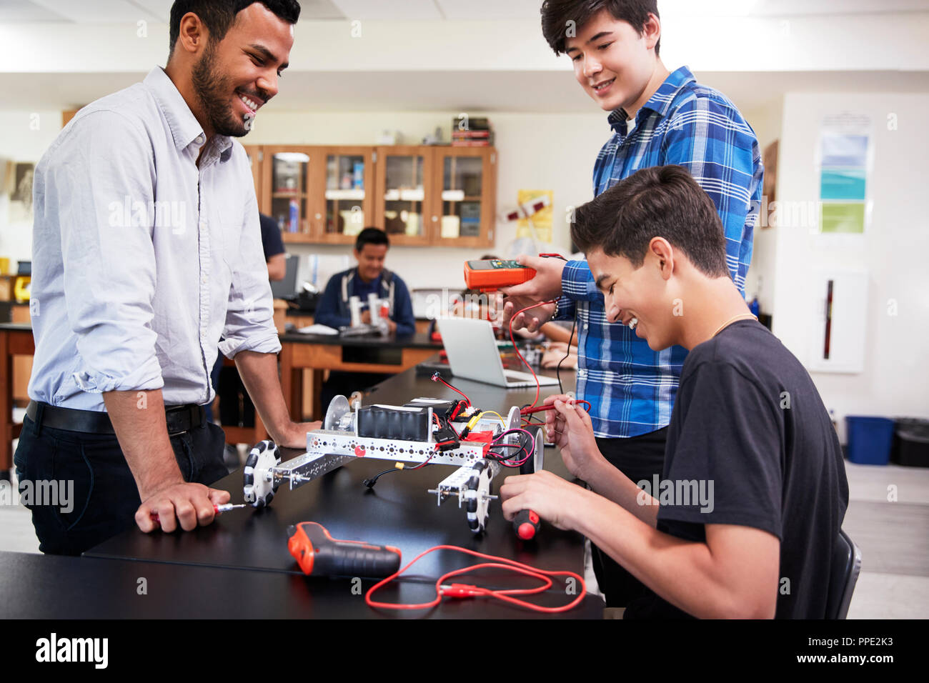 Teacher With Male Pupils Building Robotic Vehicle In Science Lesson Stock Photo