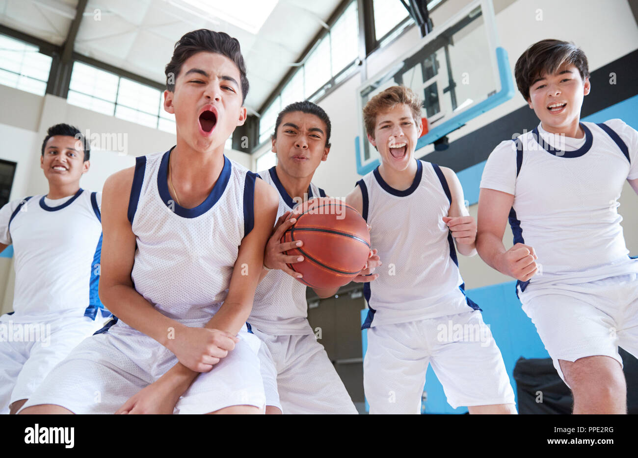 Portrait Of Male High School Basketball Team Celebrating On Court Stock