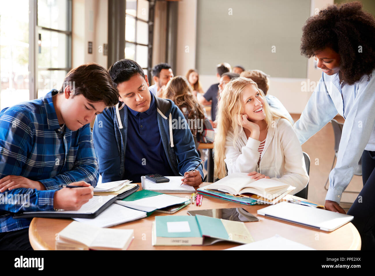 Group Of High School Students With Female Teacher Working At Desk Stock ...