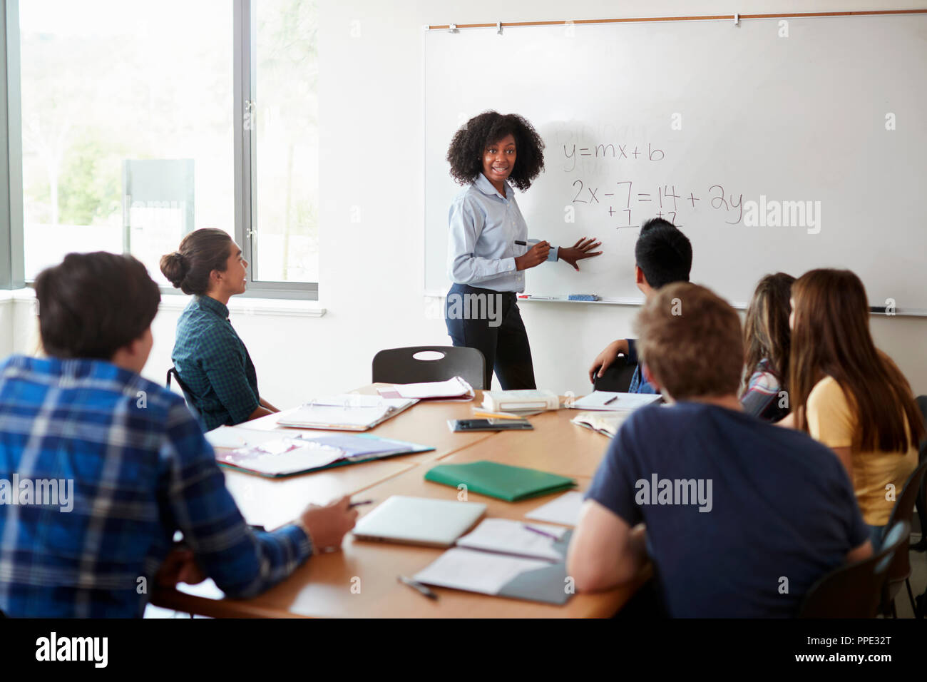 Female High School Tutor At Whiteboard Teaching Maths Class Stock Photo