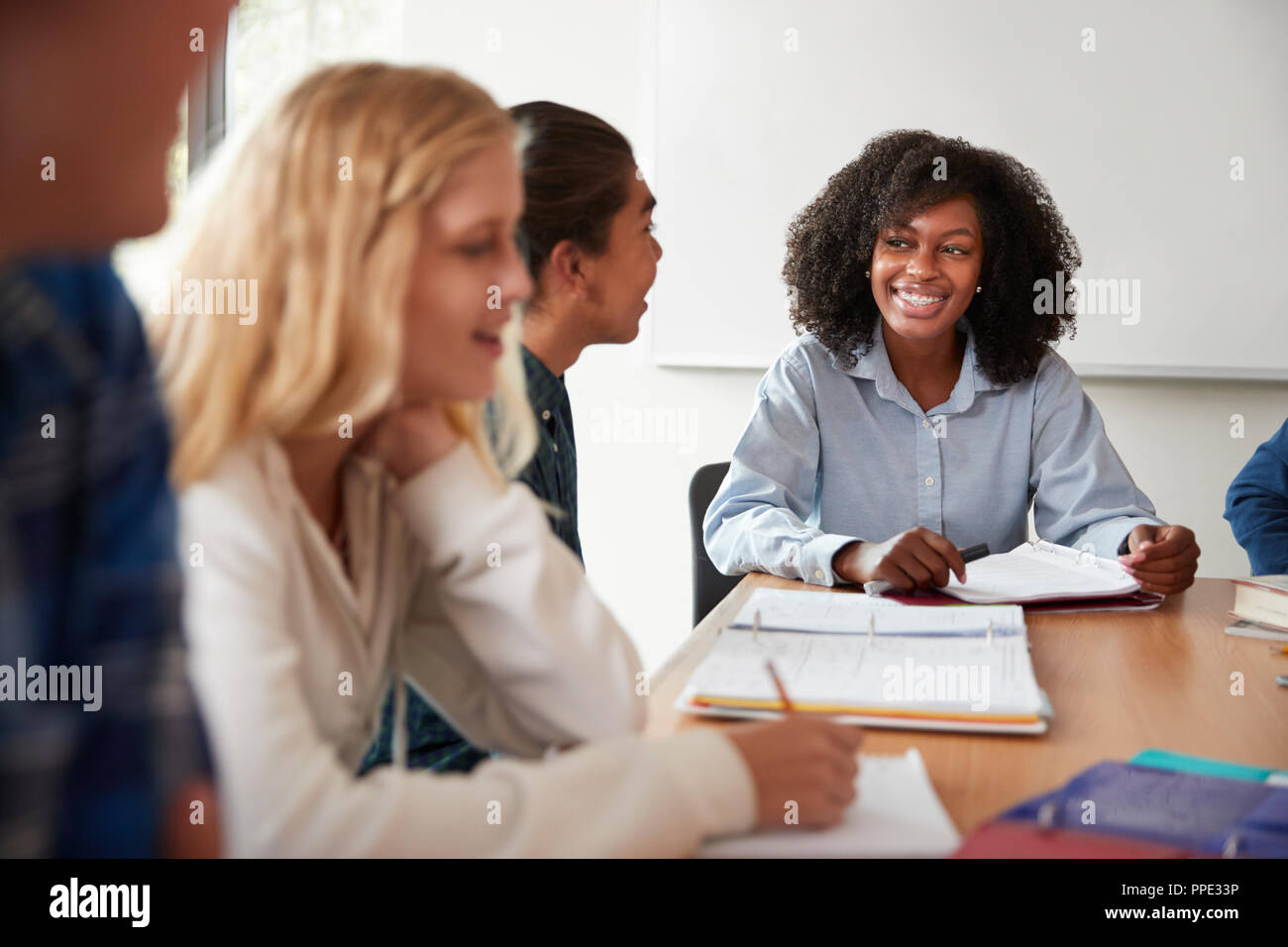 Female High School Tutor Sitting At Table With Pupils Teaching Maths Class Stock Photo