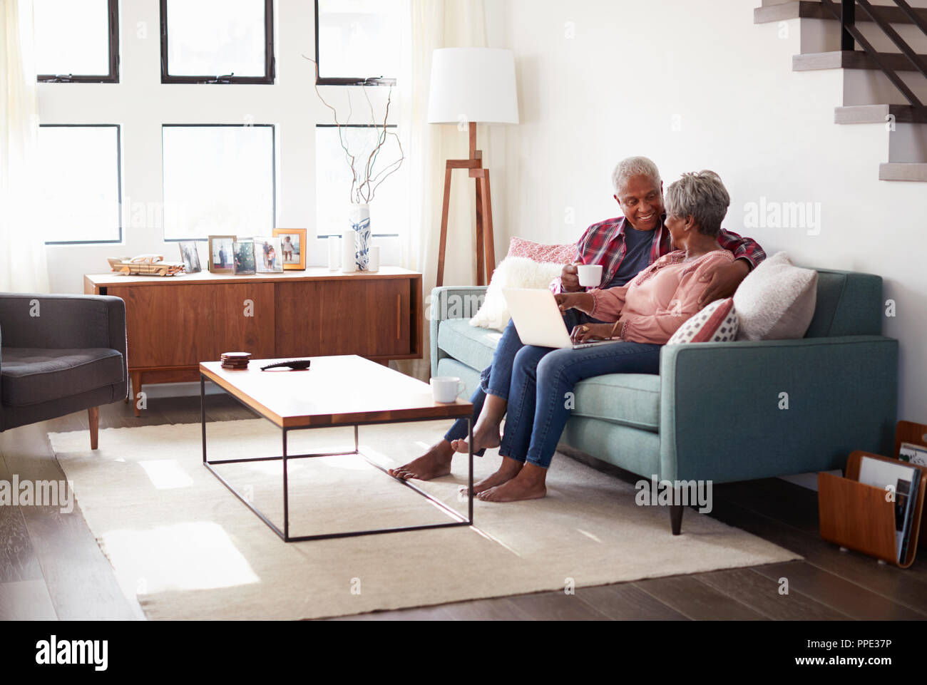 Senior Couple Sitting On Sofa At Home Using Laptop To Shop Online Stock Photo