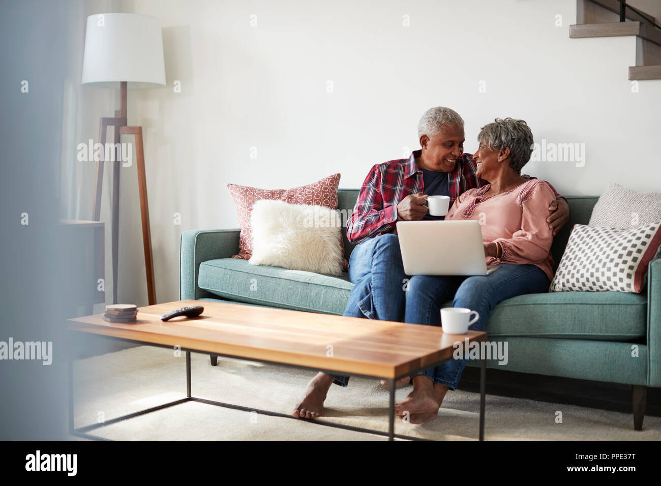 Senior Couple Sitting On Sofa At Home Using Laptop To Shop Online Stock Photo