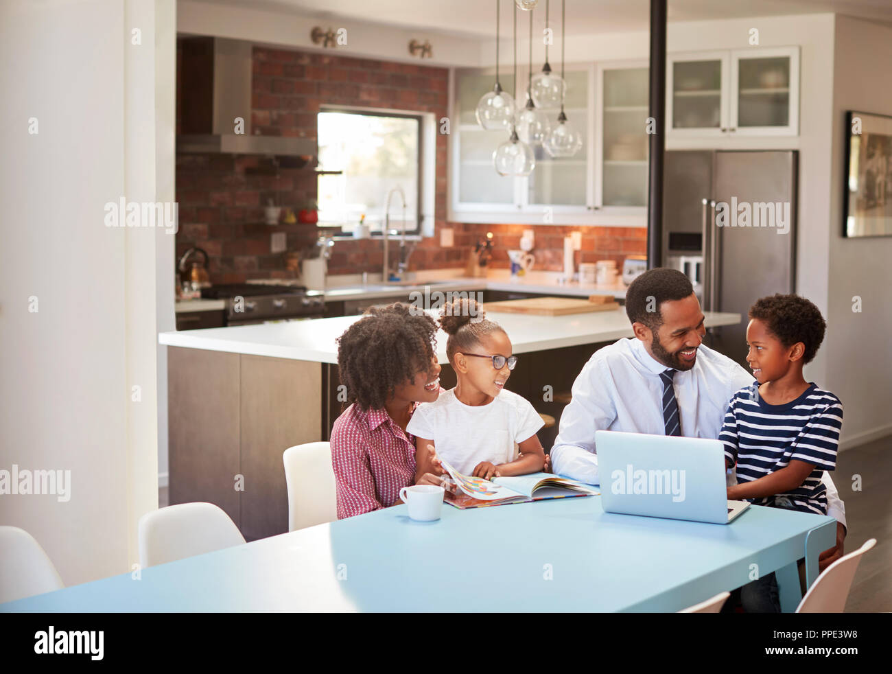 Parents Sitting Around Table At Home Helping Children With Homework Stock Photo