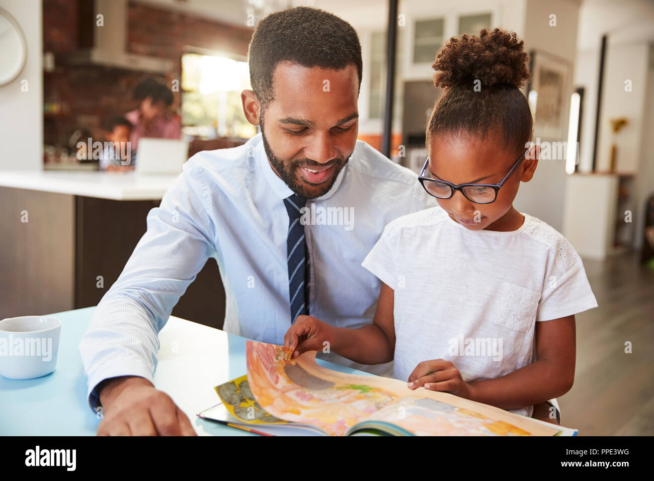 Father Reading Book With Daughter Before Going To Work Stock Photo
