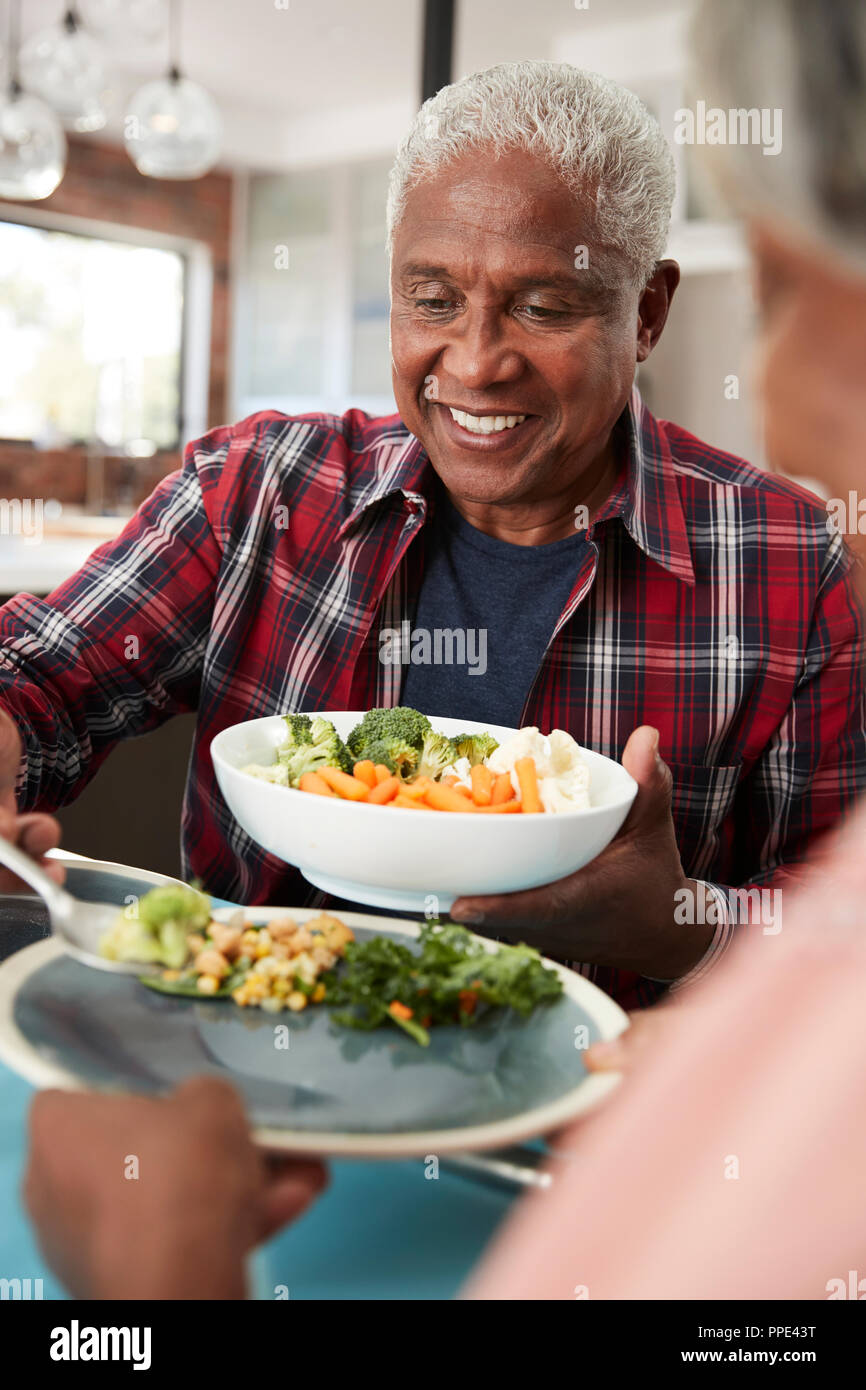 Senior Couple Enjoying Meal Around Table At Home Stock Photo