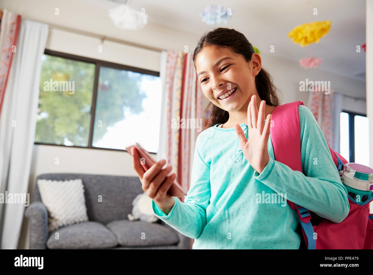 Young Girl With Backpack In Bedroom Ready To Go To School Making Video Call On Mobile Phone Stock Photo