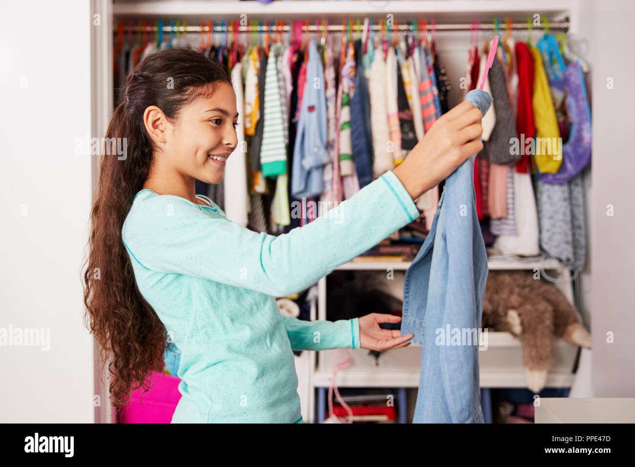 Young Girl In Bedroom Choosing Clothes From Closet Stock Photo