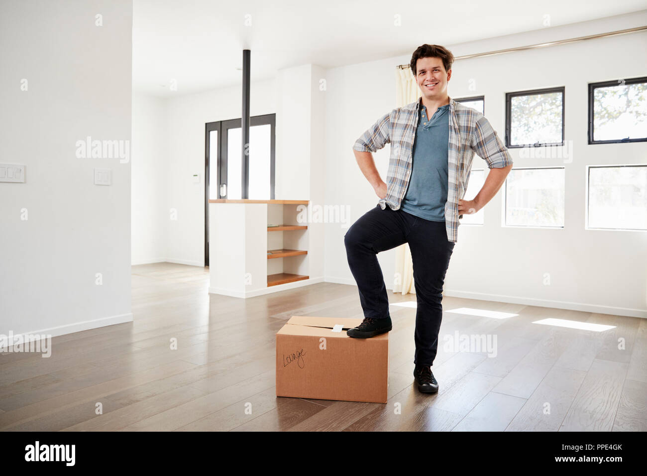 Portrait Of Proud Man Standing On Box In New Home On Moving Day Stock Photo