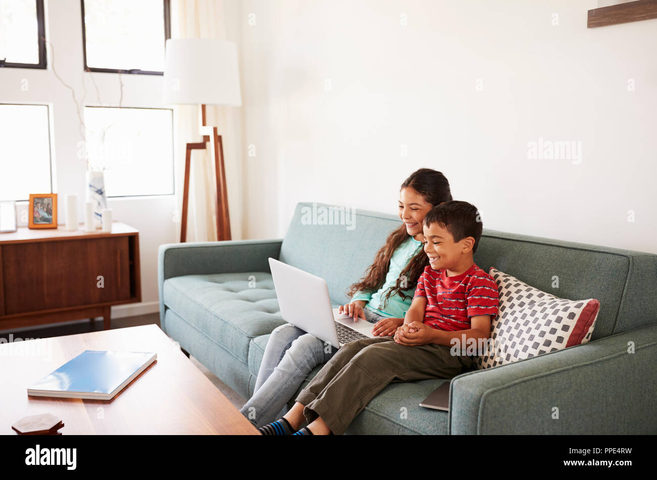 Brother And Sister Sitting On Sofa At Home Having Fun Playing On Laptop ...