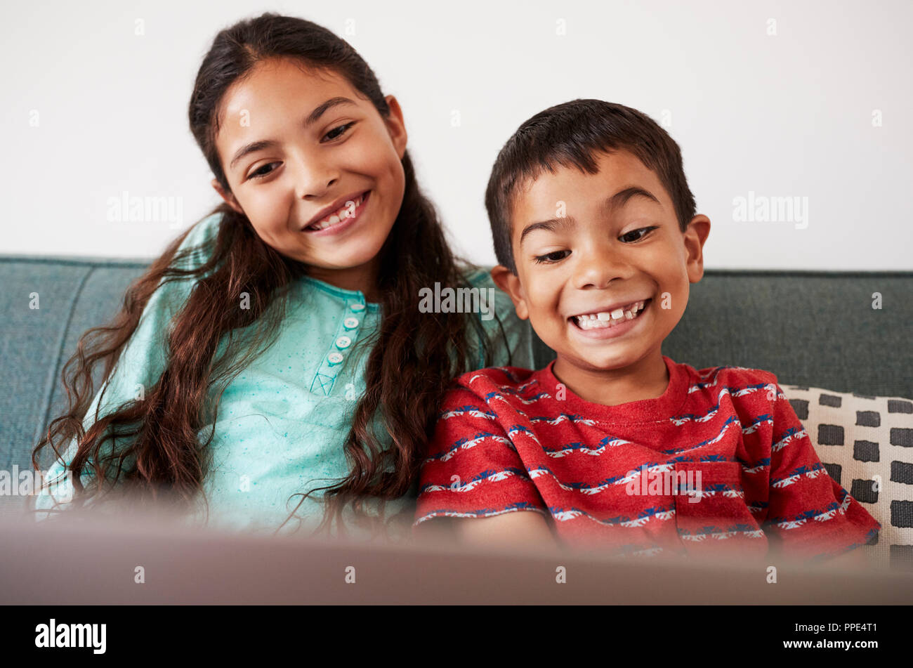Brother And Sister Sitting On Sofa At Home Having Fun Playing On Laptop ...