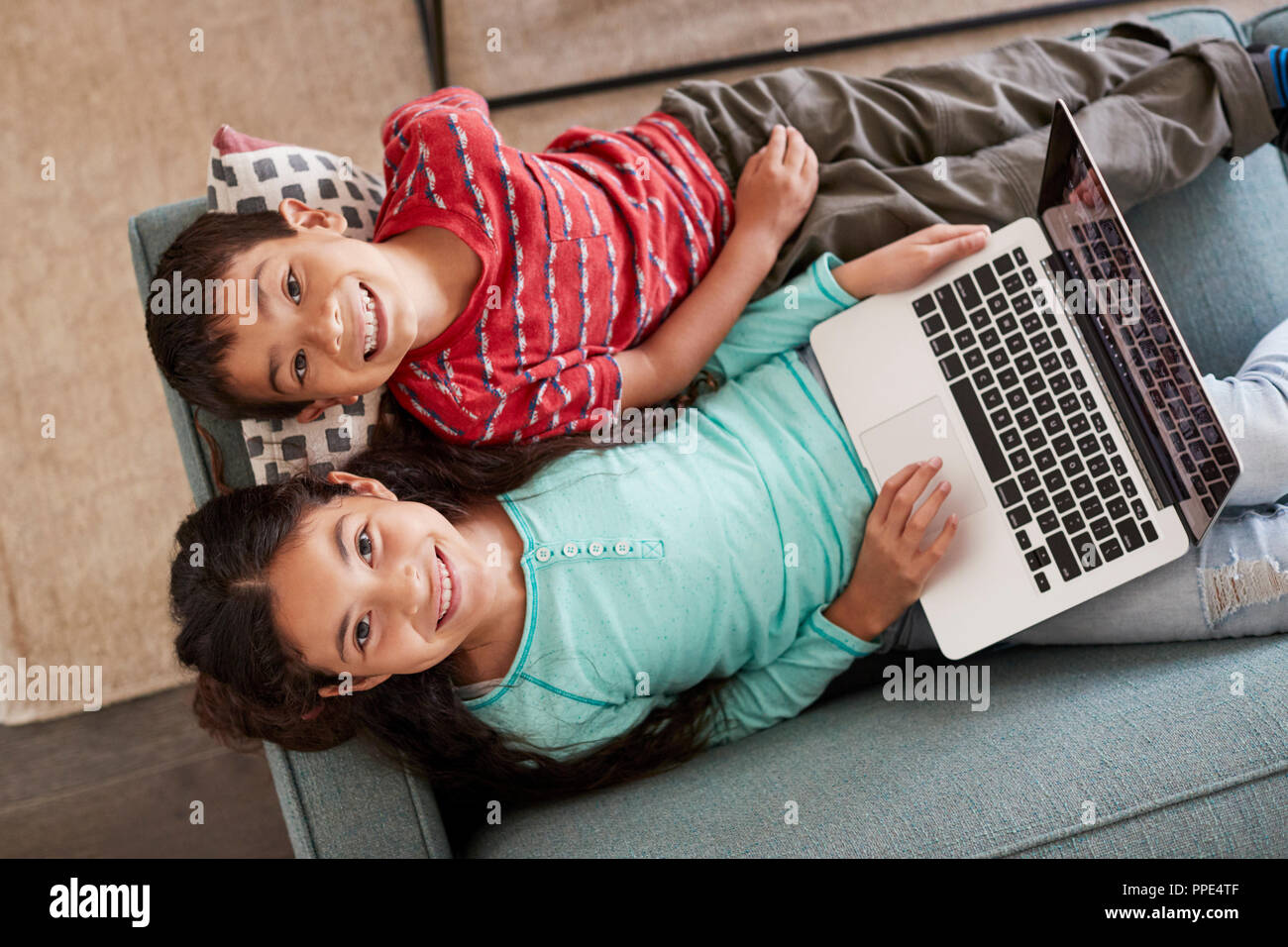 Overhead View Of Brother And Sister Sitting On Sofa At Home Having Fun ...