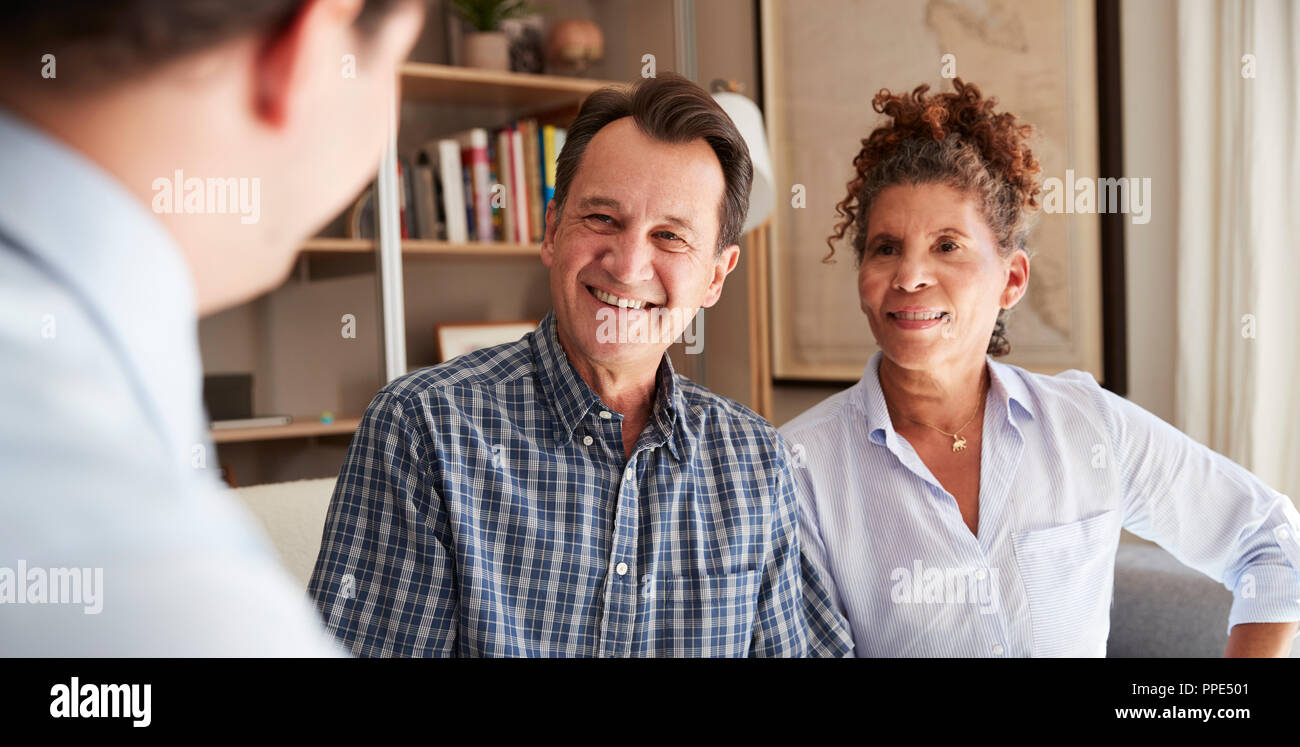Senior Couple Meeting With Male Financial Advisor At Home Stock Photo