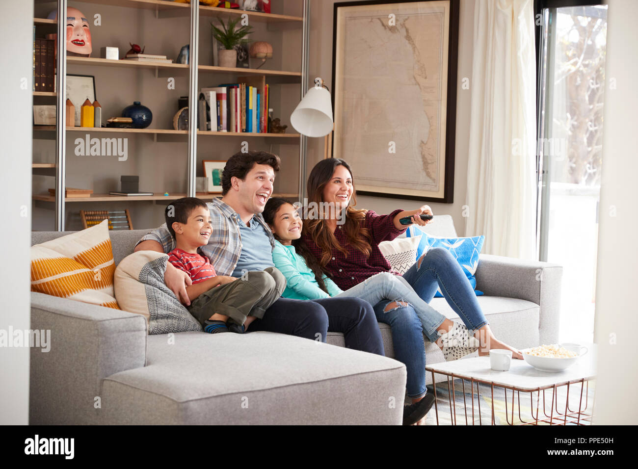 Family Relaxing On Sofa At Home Watching Television Stock Photo