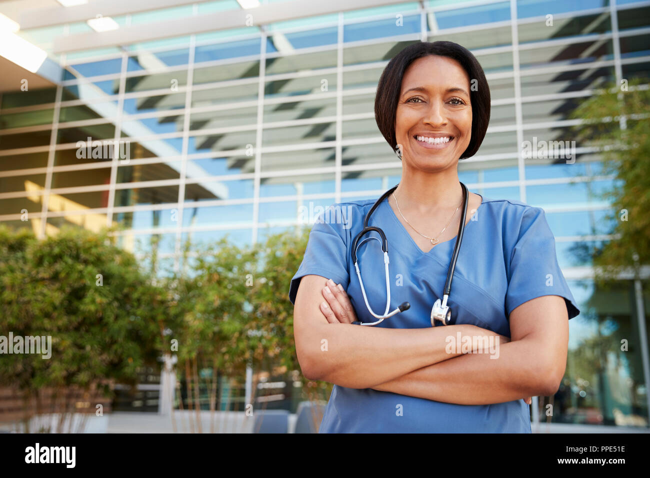 Smiling mixed race female healthcare worker outside hospital Stock Photo