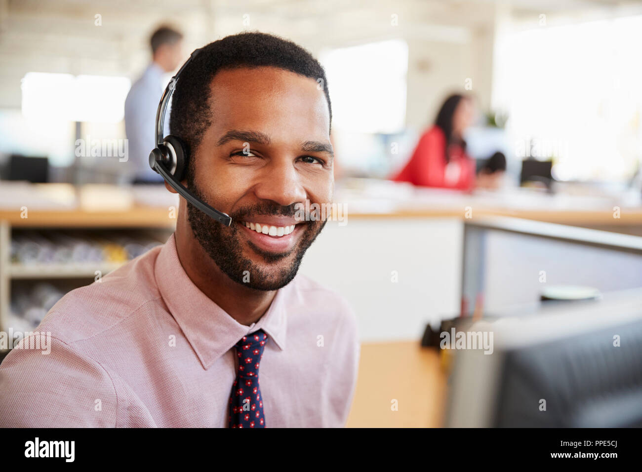 Man working in a call centre smiling to camera, close-up Stock Photo