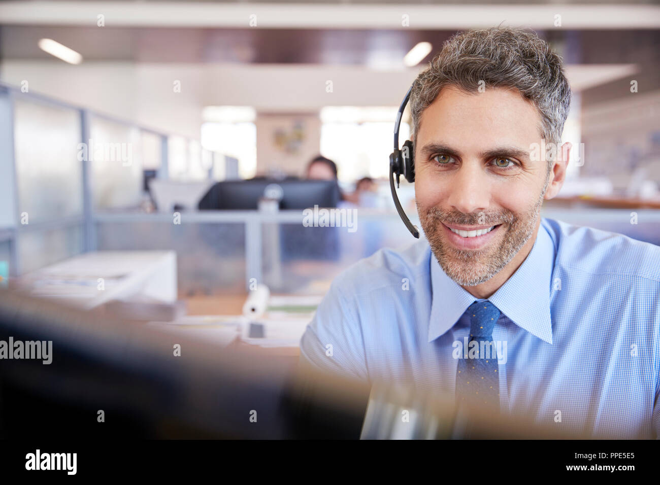 White male call centre worker looking at screen Stock Photo