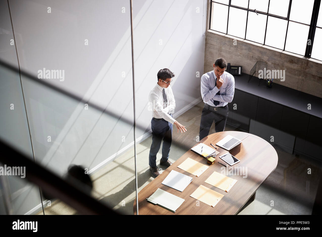 Two businessmen talk standing in an office, elevated view Stock Photo