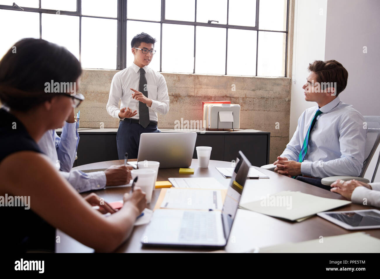 Young Asian businessman addressing colleagues at a meeting Stock Photo