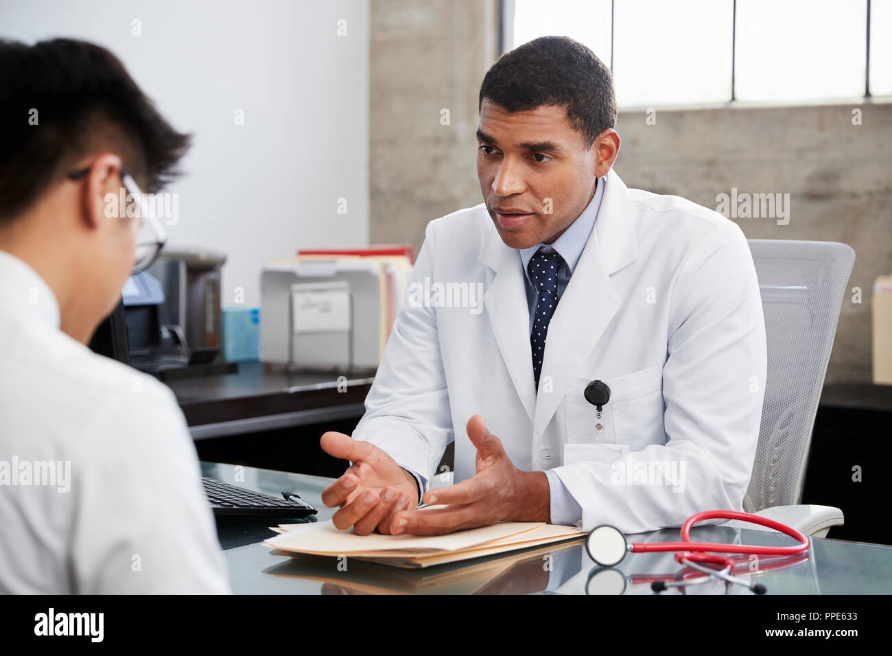 Concerned mixed race male doctor counselling male patient Stock Photo