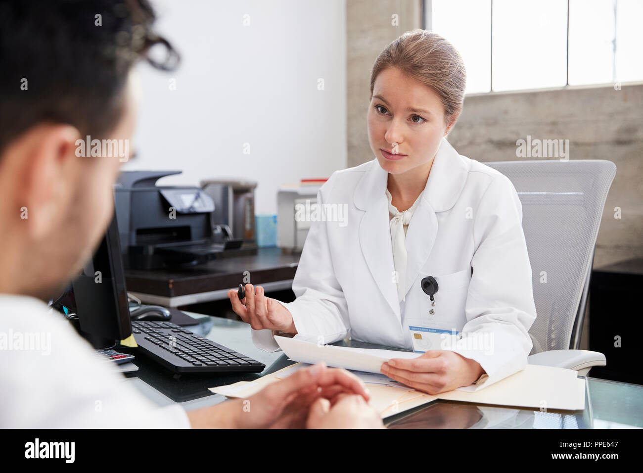 Concerned female doctor in consultation with male patient Stock Photo