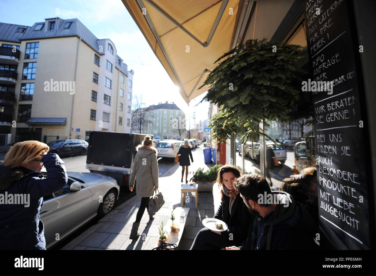 Guests sit outside the 'Aroma Coffee Bar' in the Pestalozzistrasse in Munich's Glockenbachviertel on a winter day. Christmas decorations hang in front of the windows. Stock Photo
