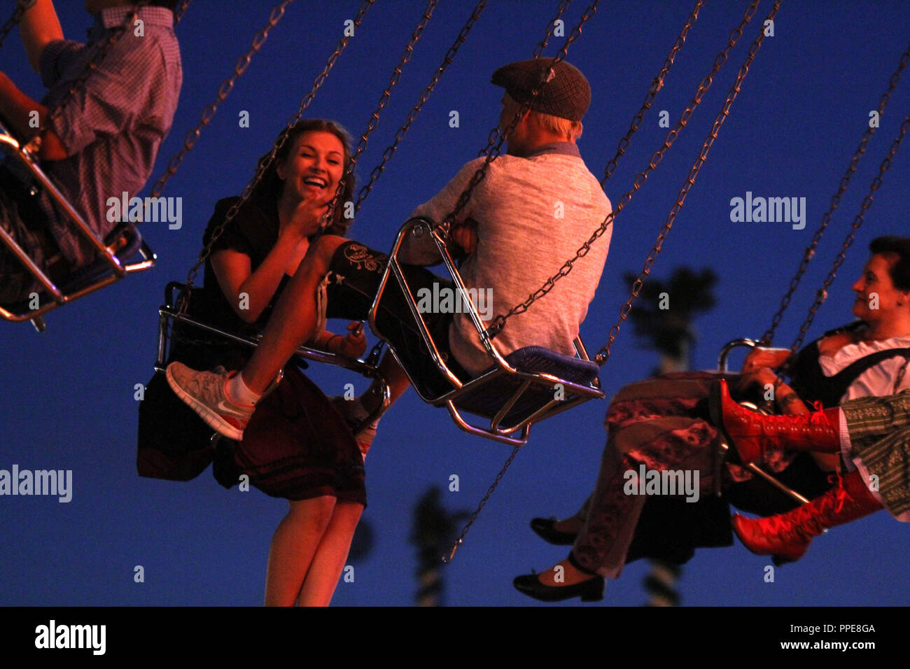 Oktoberfest visitors on a swing ride at dusk on the 'Oidn Wiesn'. Stock Photo