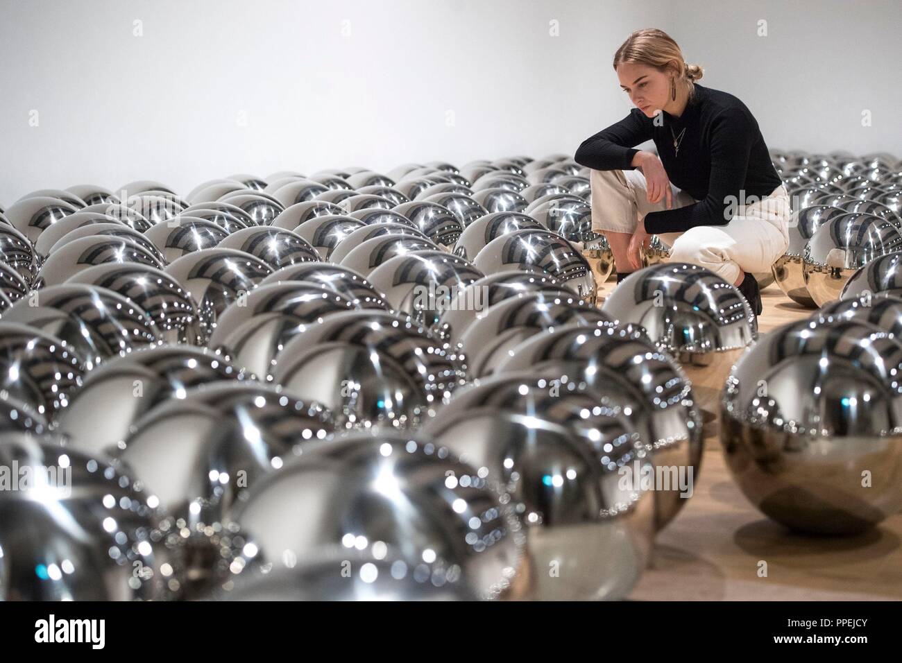 A woman views 'Narcissus Garden 1966-' by Yayoi Kusama, made of stainless steel spheres, during a press preview for the exhibition: Space Shifters at the Hayward Gallery, Southbank Centre, London. Stock Photo