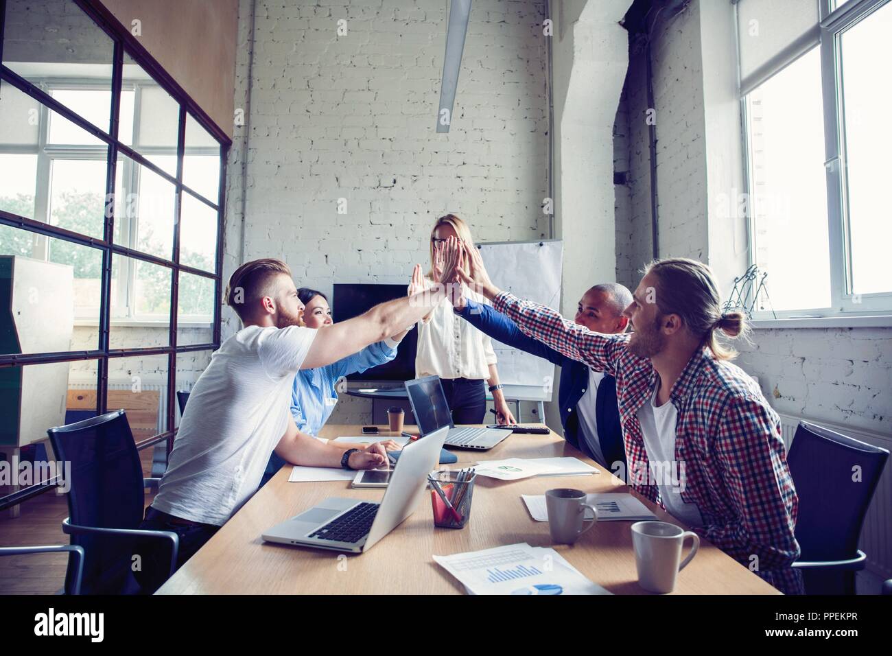 Colleagues Giving High-Five Celebrating Business Success Standing In Office  Stock Photo by ©Milkos 381522740