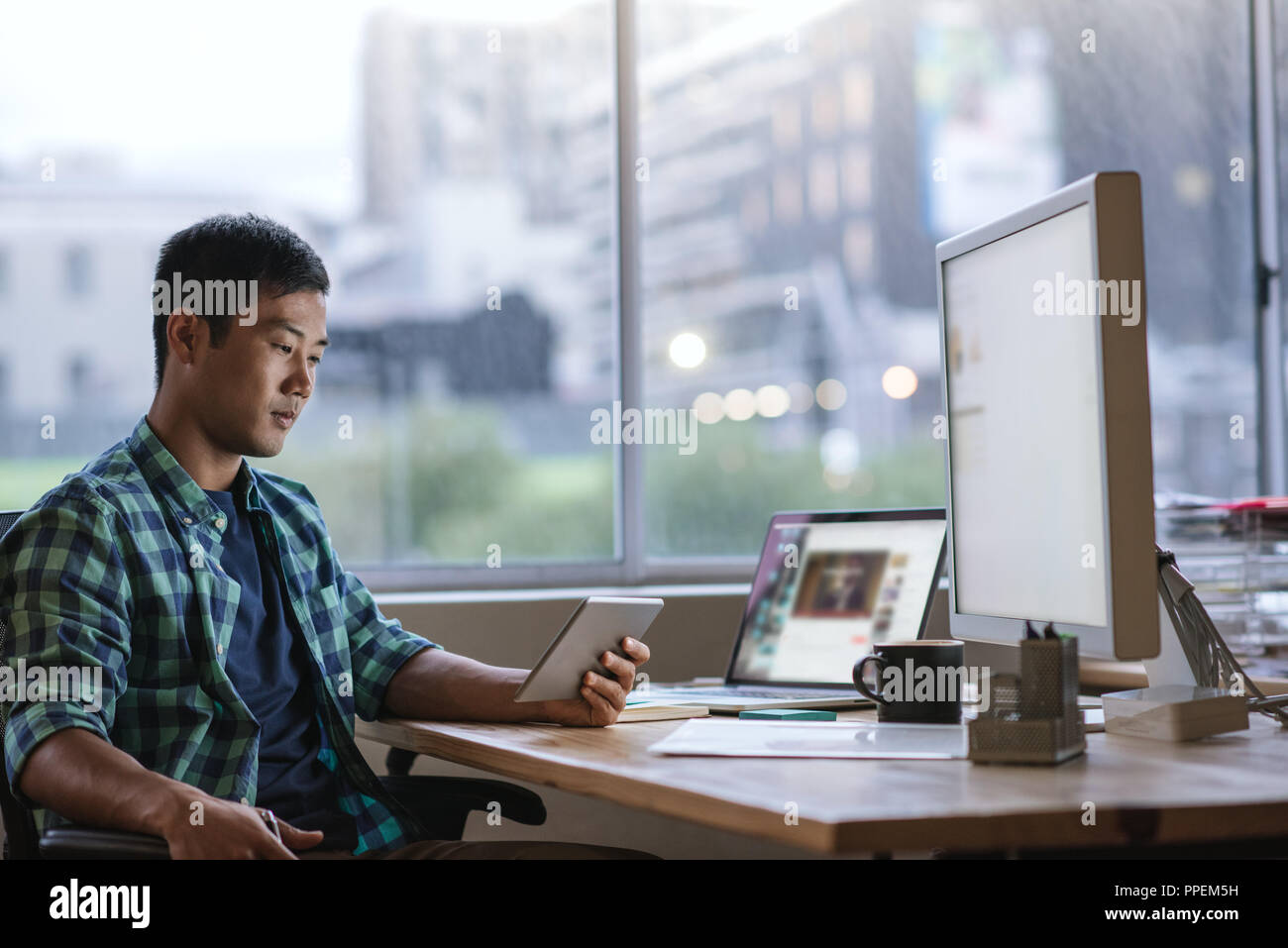Young Asian designer using a tablet at his desk Stock Photo