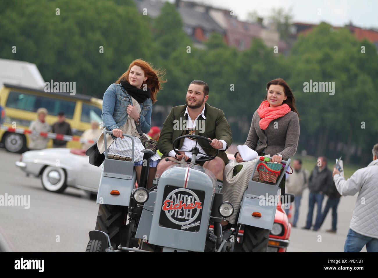 A man and two women on an old Eicher tractor at the 11th Classic Car Meeting of the Automobile Club Munich (ACM), which takes place parallel to the Spring Festival on the Theresienwiese. Stock Photo