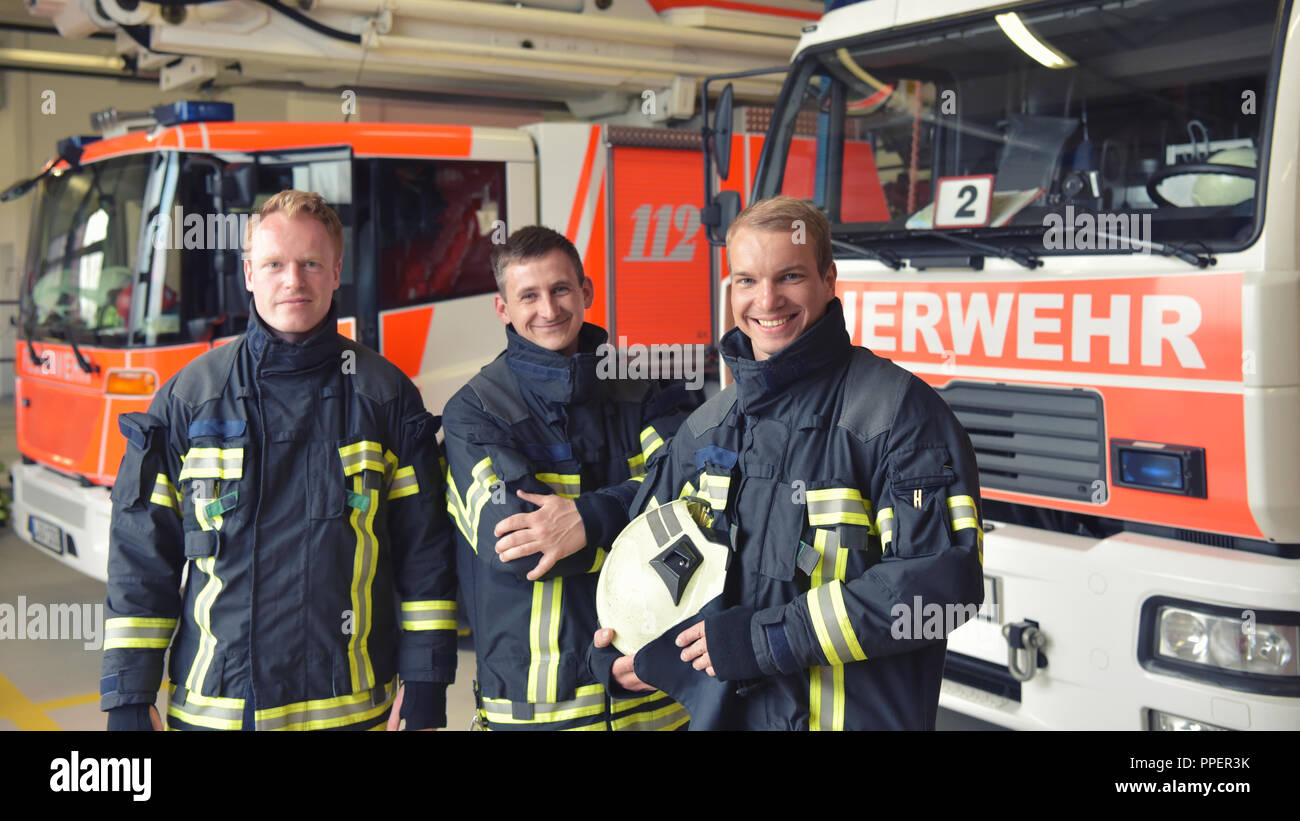 Group of firefighters at the emergency vehicle in the fire station Stock Photo