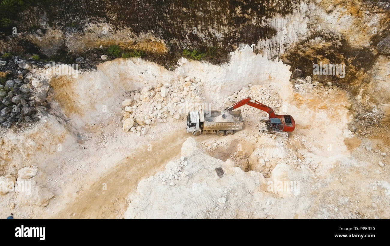 Excavator loads the truck in a limestone quarry. Aerial view wheel