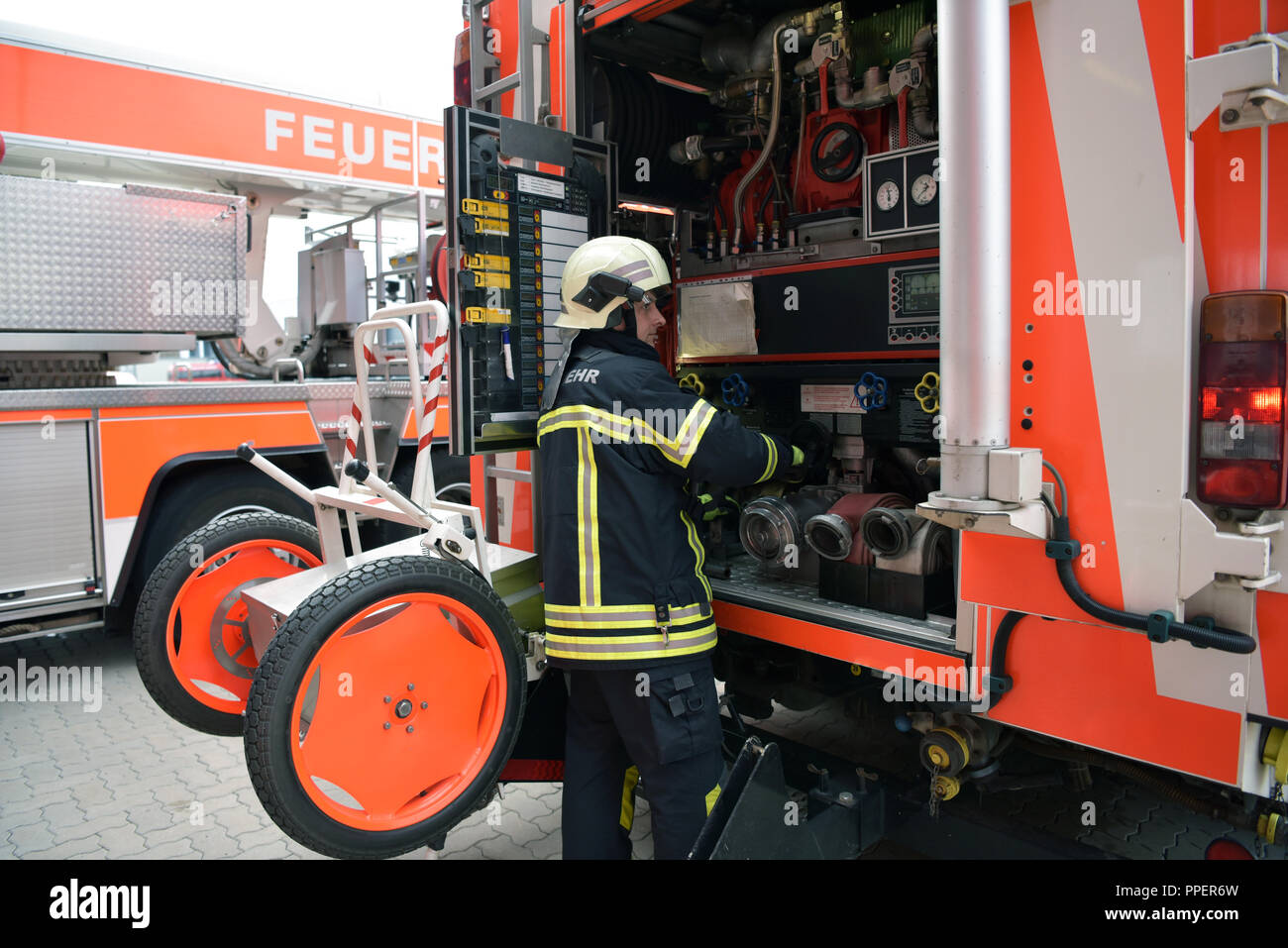 Group of firefighters at the emergency vehicle in the fire station Stock Photo