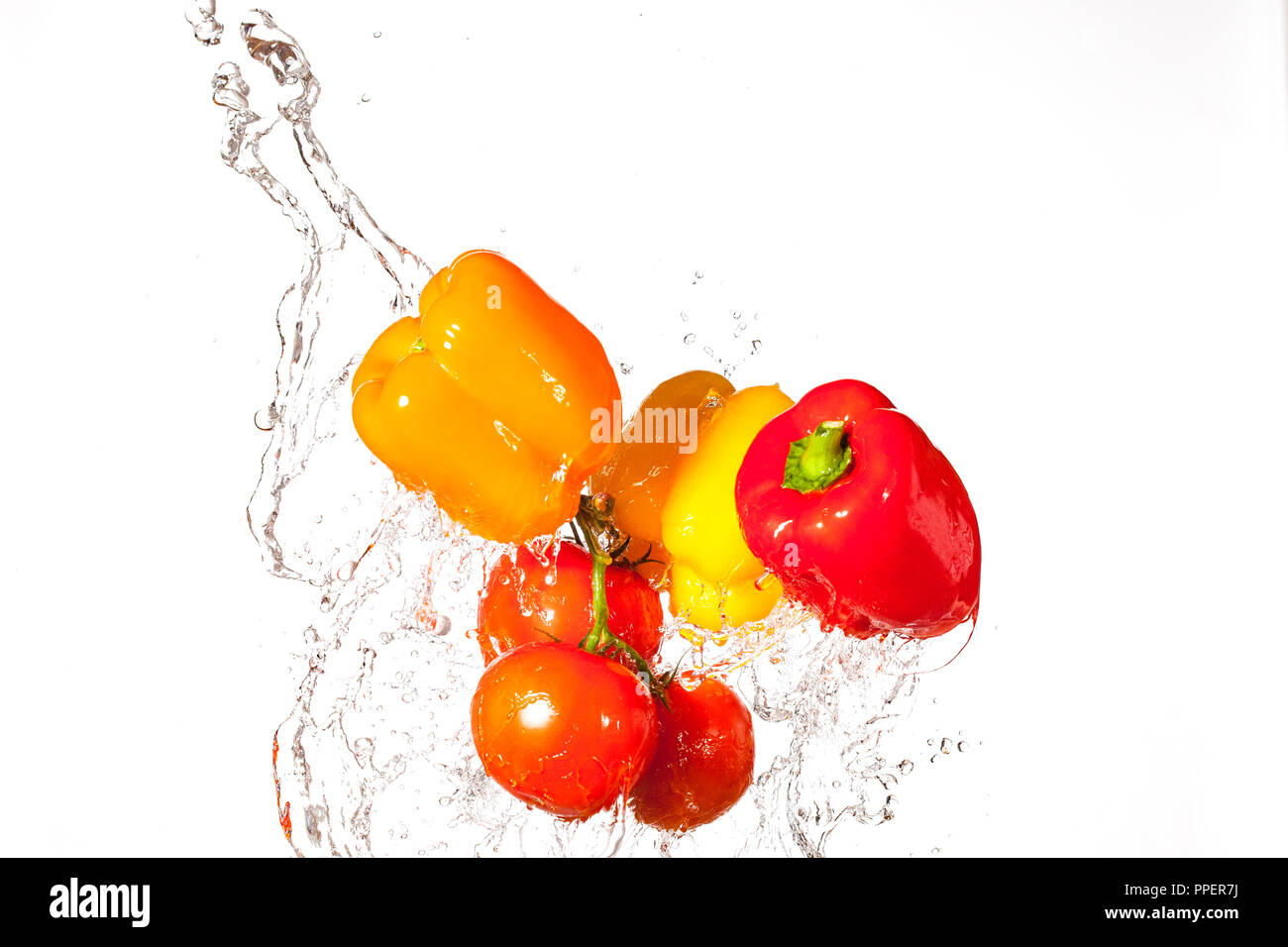 Fresh Peppers and Tomatoes Splashing Through Water Stock Photo