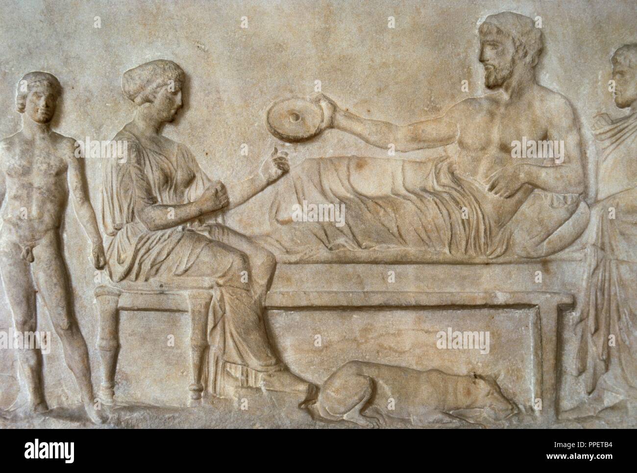 Greek art. Classical period. Grave stele. Relief. Funerary banquet scene. The man lying holding in his hand a 'Philae' and a boy came from a crater serves. Dated in 400 BC, was found in the Asklepieion (Piraeus). National Archaeological Museum. Athens. Greece. Stock Photo