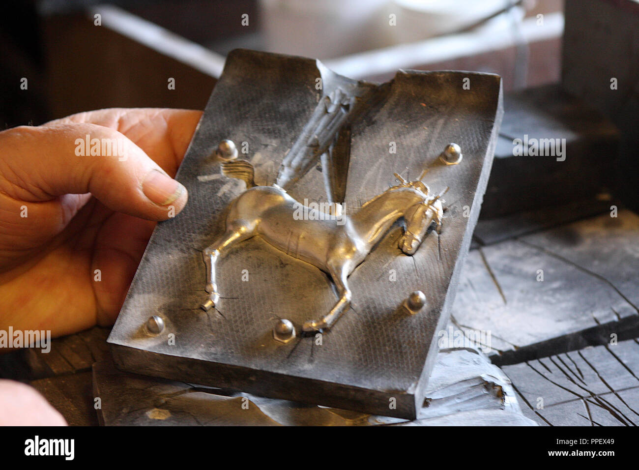 Tin figure producer and collector Erich Eder when making a tin horse: the casting of a horse in the rubber mold. Stock Photo