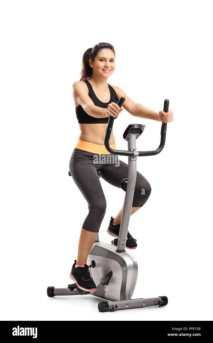 Full length portrait of a young female riding a stationary bike isolated on white background Stock Photo