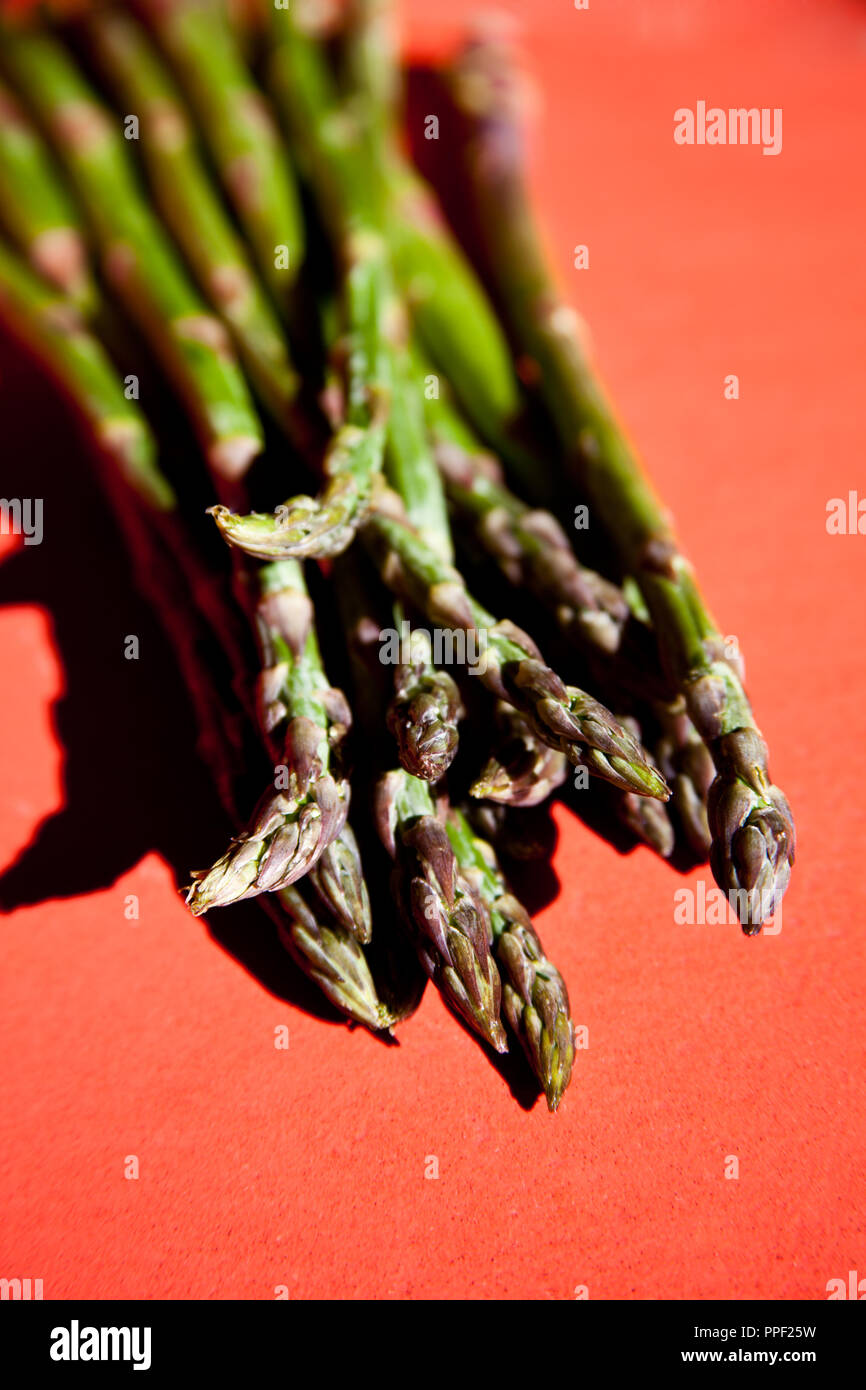 bunch of fresh green asparagus spears on a red table Stock Photo - Alamy