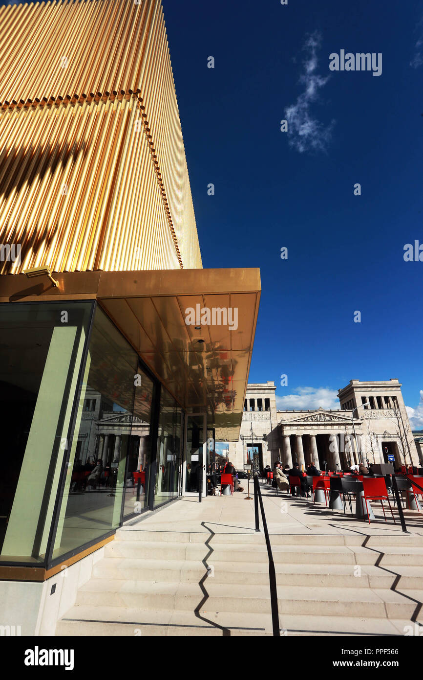 Guests on the terrace of the museum restaurant 'Ella' in front of the extension of the Lenbachhaus with its shining golden facade. In the background the Propylaea on Koenigsplatz. Stock Photo