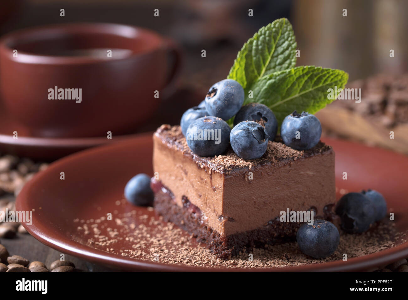 Chocolate cake with blueberries and mint on a brown plate Stock Photo ...