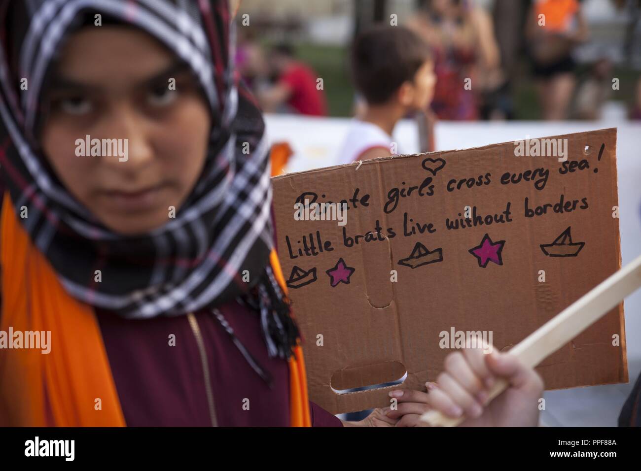 Refugee child with sign 'Pirate girls cross every sea. Little brats live without borders' during rally in Athens against omission of Sea Rescue. 01.09.2018 | usage worldwide Stock Photo