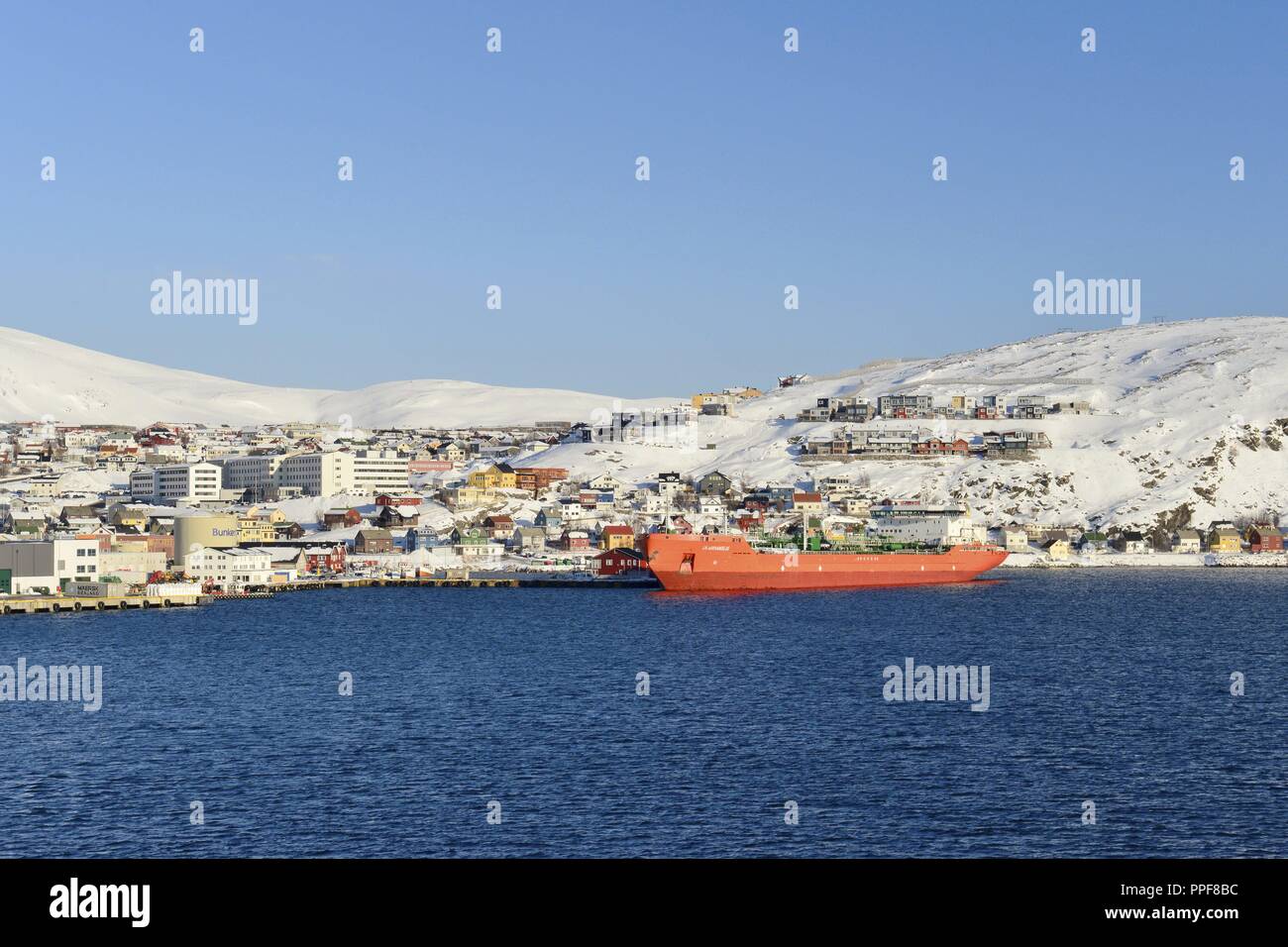 The bay of Hammerfest with a big red ship in front of the town's buildings on the snow white slopes from the island Kvaløy, 9 March 2017 | usage worldwide Stock Photo