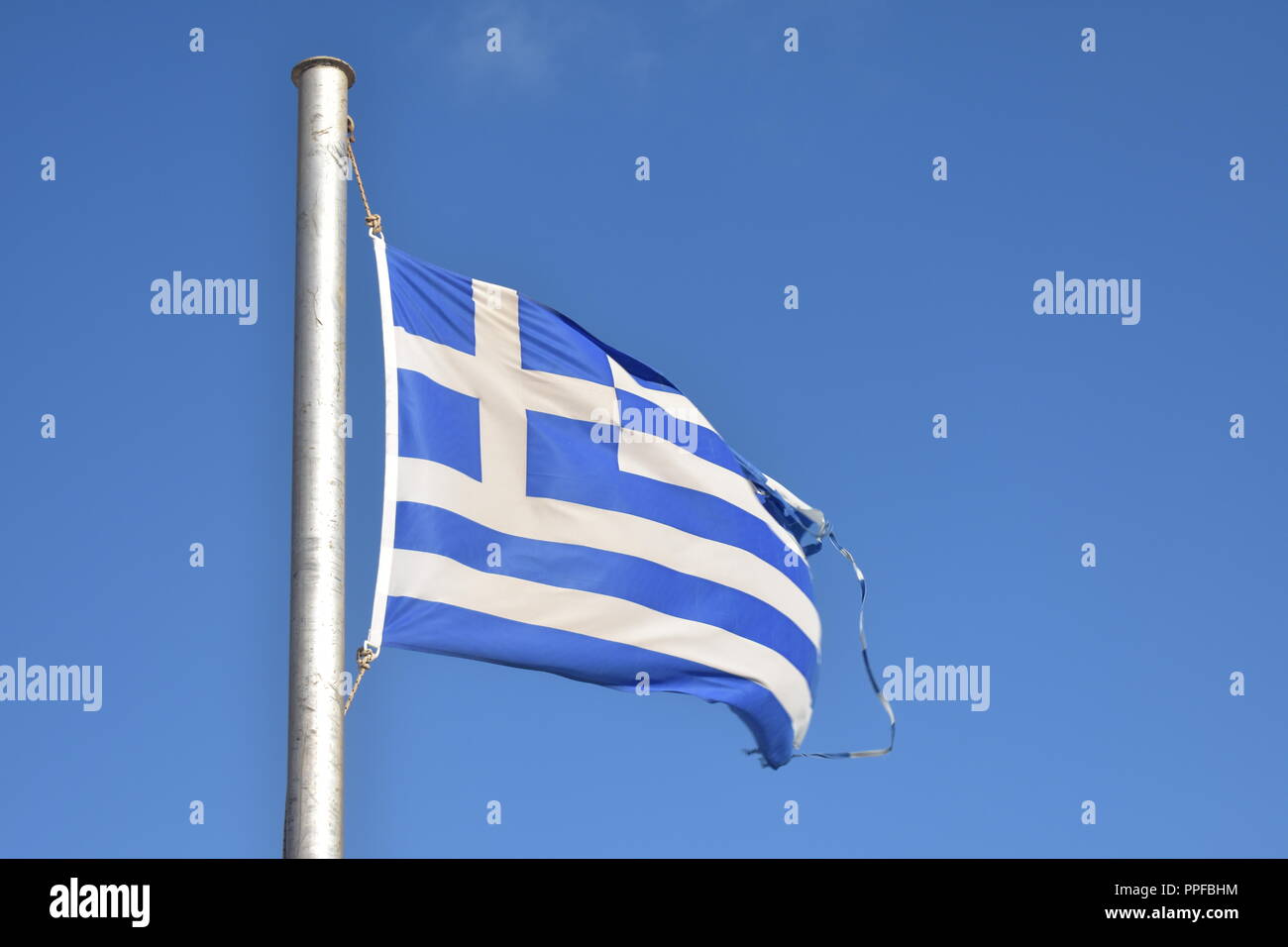 Greece, the beautiful island of Ios.  The Greek flag flutters proudly in the summer breeze, set against a deep blue sky. Stock Photo