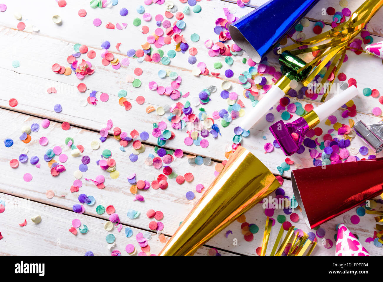 Party background. Party caps and confetti on white wooden background. Copyspace Stock Photo
