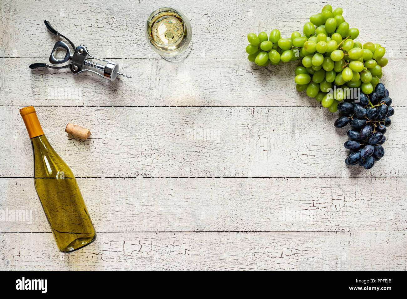 White wine with grapes on a weathered, peeling white wood table Stock Photo
