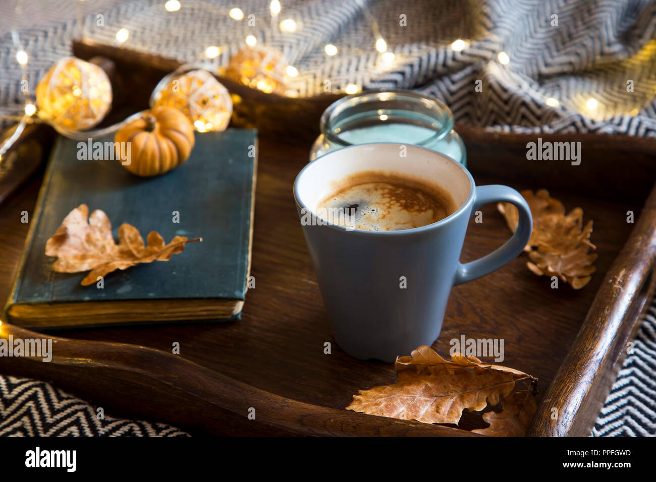 Cozy autumn setting with cup of cofee , book , candle and lights in a  wooden tray and a blanket Stock Photo - Alamy, image size:1300x956