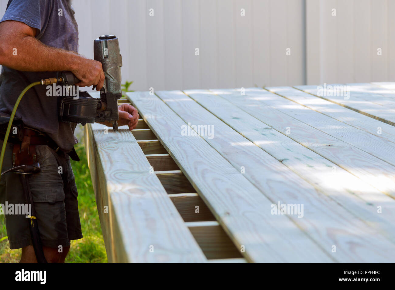 Building a backyard deck with worker putting with nail gun deck boards