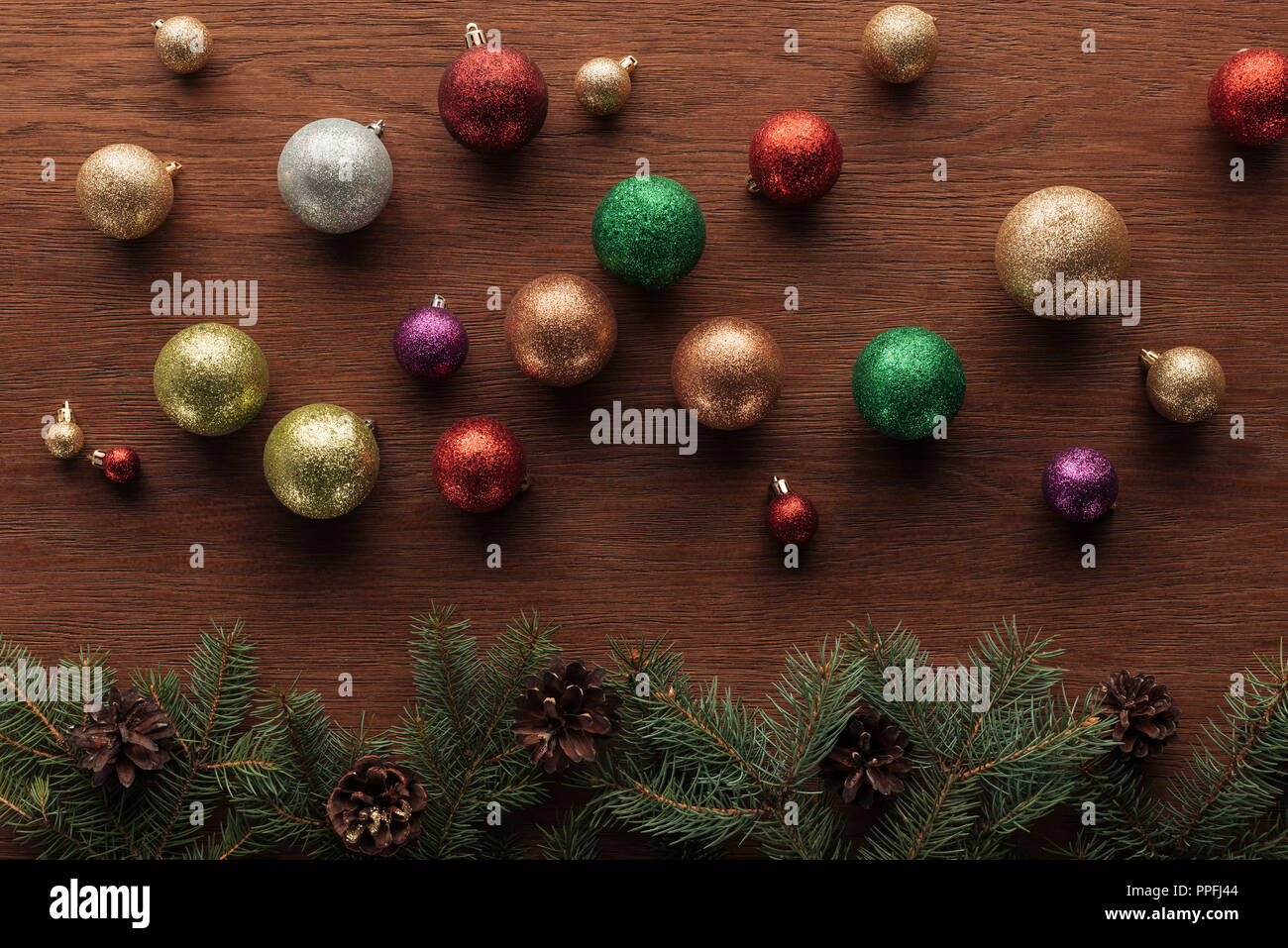 shiny colorful balls and coniferous twigs with pine cones on wooden background Stock Photo